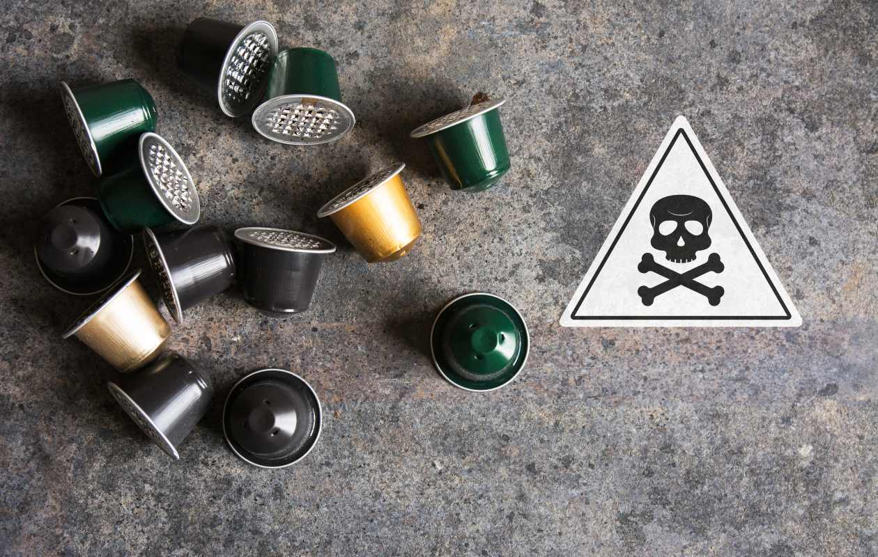 Cápsulas de café junto a un símbolo de peligro con una calavera sobre una superficie metálica - Memento Coffee